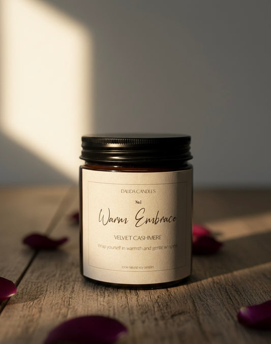 No.1 Velvet Cashmere candle, Warm Embrace, with notes of Tobacco whiskey, set on wooden surface with rose petals.